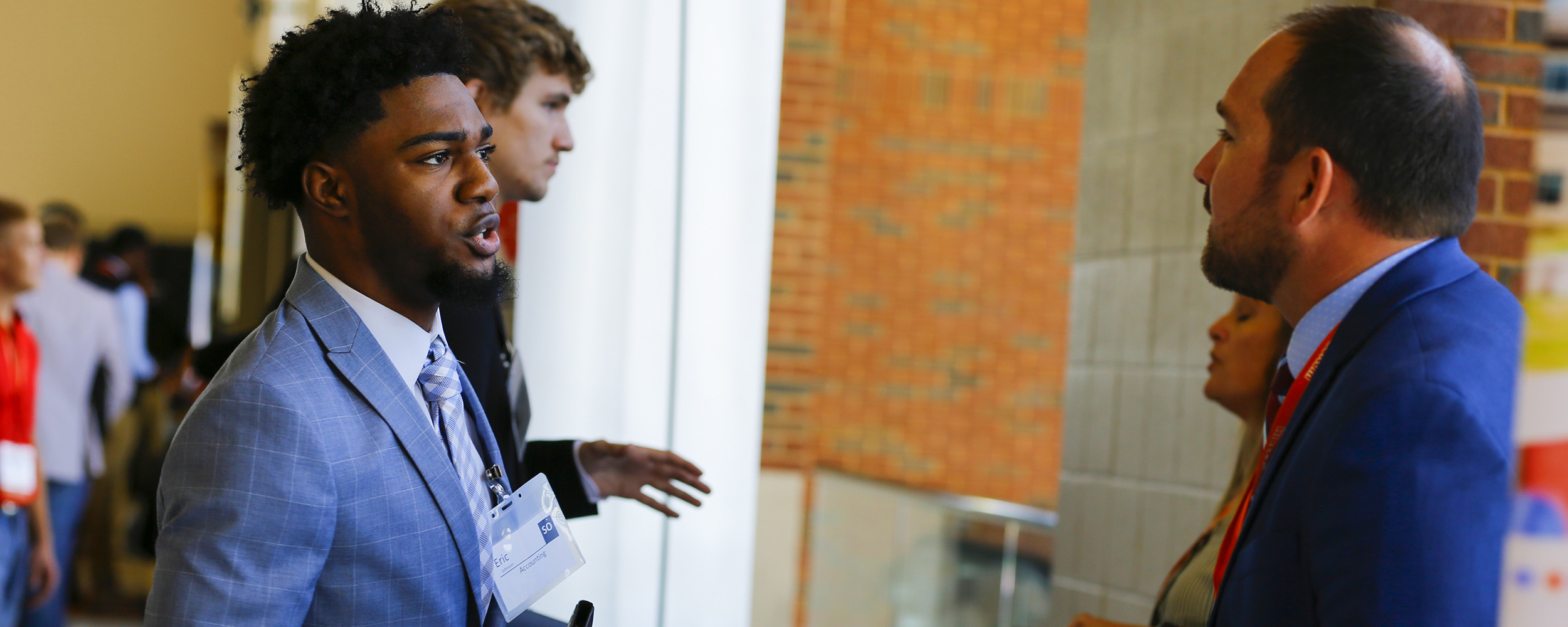 Student in business professional attire speaking with a recruiter. 