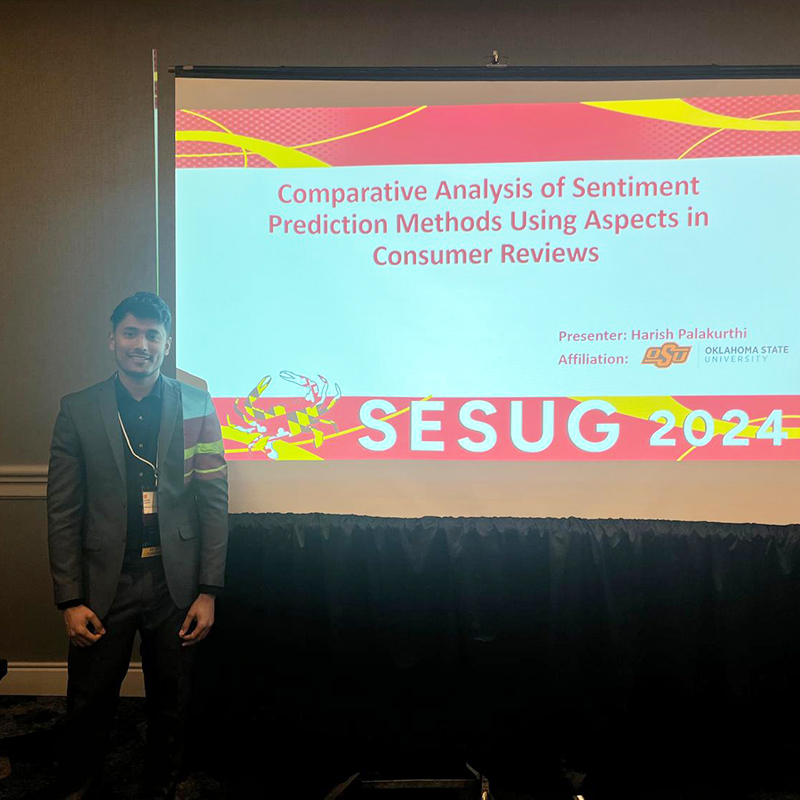 Harish Palakurthi stands next to a screen displaying his PowerPoint presentation of his research paper, which earned a top-5 paper award at SESUG.