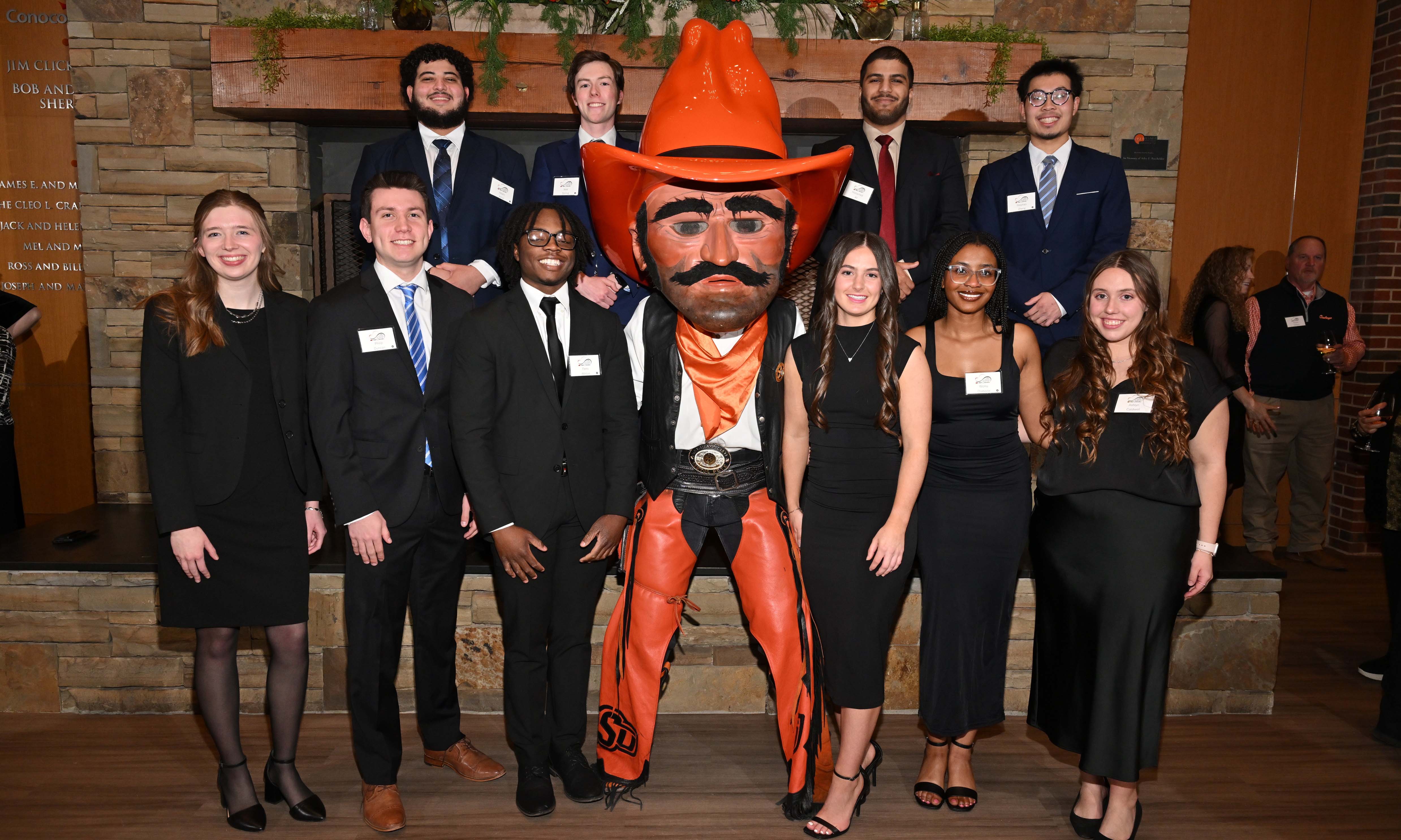 Group of students dressed professionally posing with the Pistol Pete mascot. Group of students dressed professionally posing with the Pistol Pete mascot.