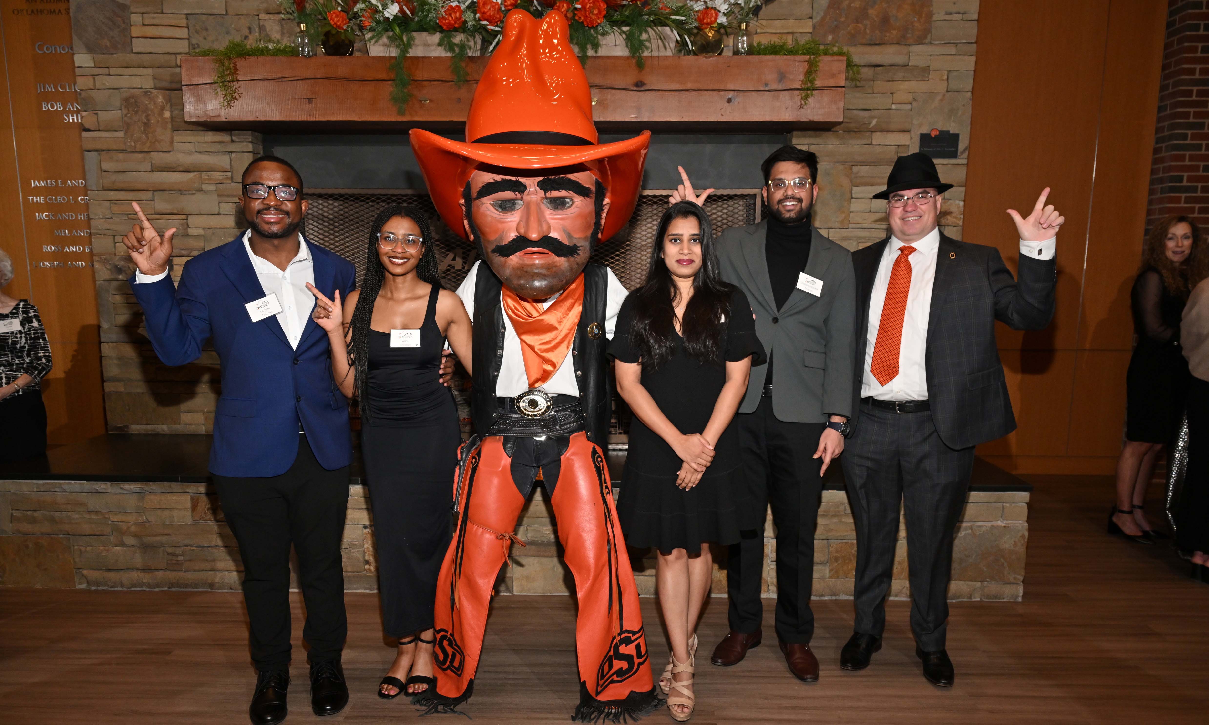 Graduate students and a professor posing with Pistol Pete. Graduate students and a professor posing with Pistol Pete.