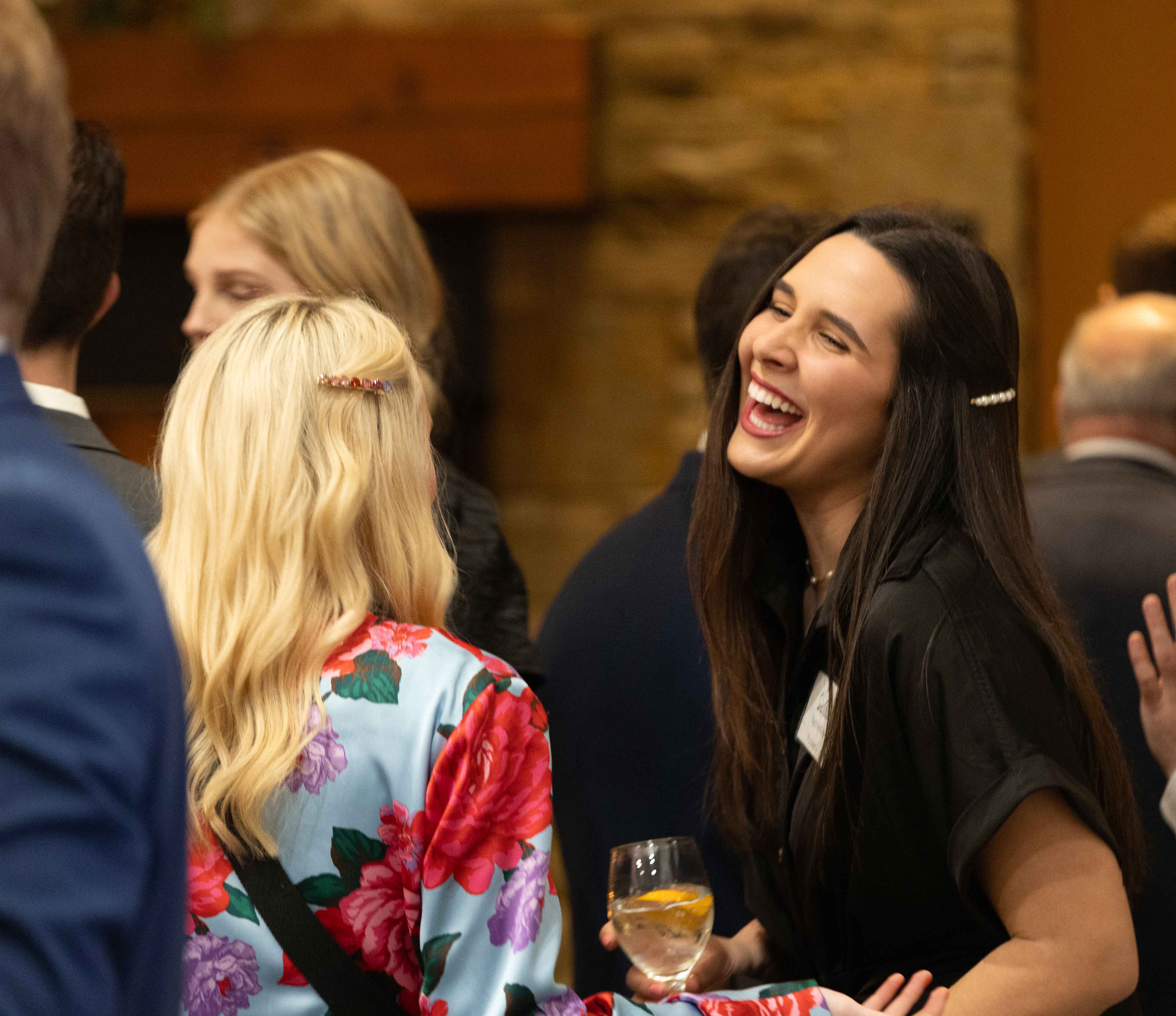 Female student dressed professionally speaking with someone and laughing in the lobby of the alumni center. Female student dressed professionally speaking with someone and laughing in the lobby of the alumni center.