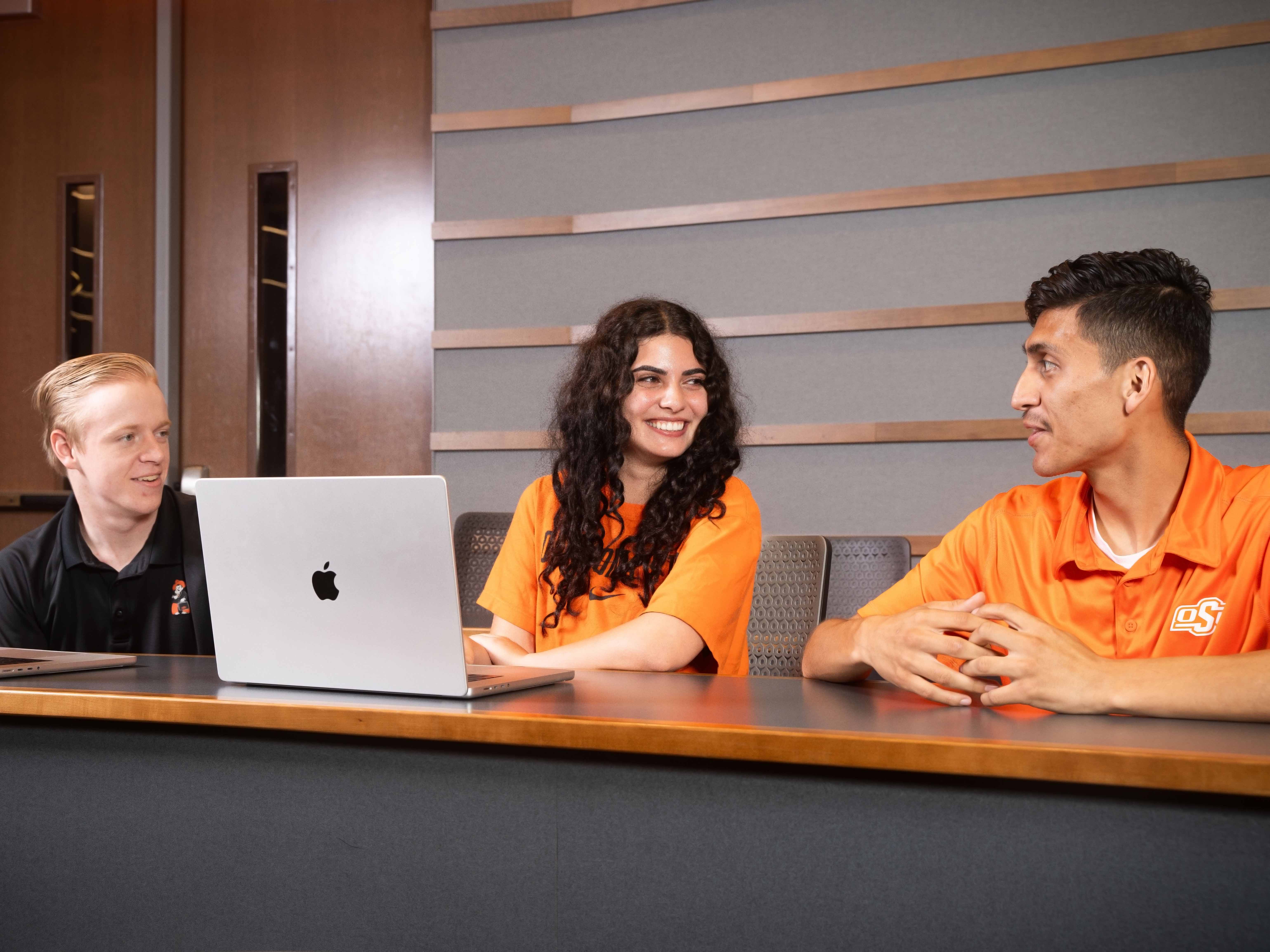 Three students working on a laptop and smiling